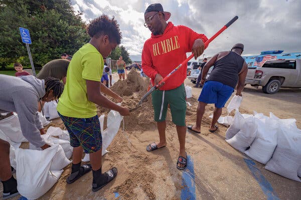Jawan Williams shoveled sand for a sandbag held by his son Jayden Williams at the Frederick Sigur Civic Center in Chalmette, La., on Saturday.