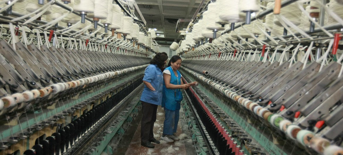 Two women check industrial looms in a rug factory in Mongolia.