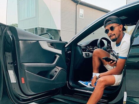 Kenyan footballer Handwalla Bwana poses for a photo inside his car. 