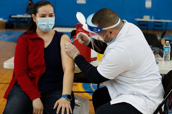 Peter Cooper Public School teacher Lizbeth Osuna, left, receives a Moderna COVID-19 vaccine in Chicago in Feb.