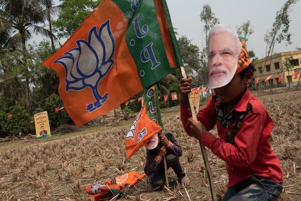 Children wearing masks with the face of Prime Minister Narendra Modi in Nandigram, India, in March. A second virus wave has made India the worst-hit country in the world, shaking Mr. Modi’s image of strength.