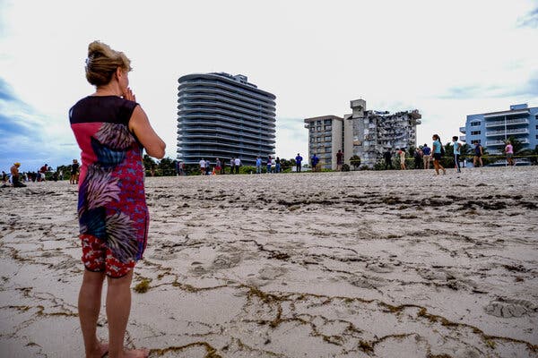 A woman praying in front the Champlain Towers in Surfside, Fla. yesterday. Many charities began coordinating donations.