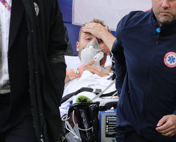 Eriksen appeared to be awake, and holding his hand to his forehead, as he was carried from the field.