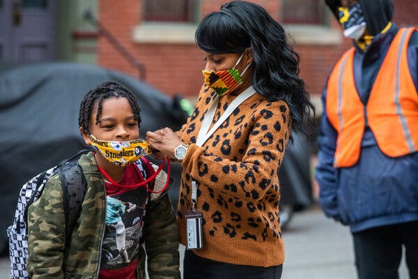 Jenea Edwards helps her son with his mask before heading into school in Pittsburgh in March.