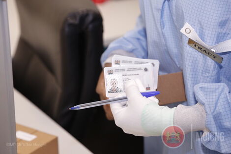 A worker holding a Huduma Namba card at a mass printing facility in Nairobi