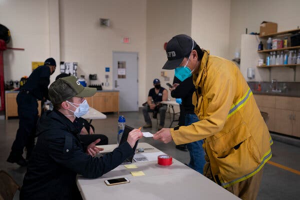 Firefighter Henry Hsieh picks up a vaccination card before getting his second dose of the Covid-19 vaccine at a fire station in Los Angeles, in January.