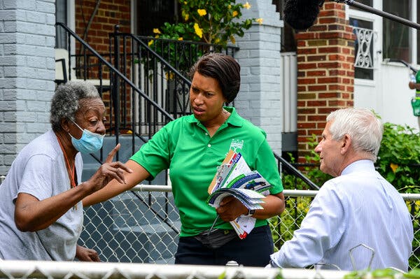 Dr. Anthony S. Fauci, right, and Mayor Muriel E. Bowser of Washington, center, went door-knocking in the city’s Anacostia neighborhood on Saturday to encourage residents to get vaccinated.
