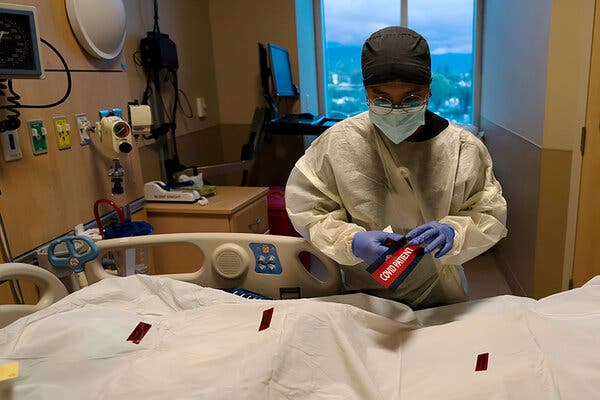 Bryan Hofilena, a registered nurse, attaching a “Covid patient" sticker to the body bag of a patient who died of Covid at Providence Holy Cross Medical Center in Los Angeles in December.