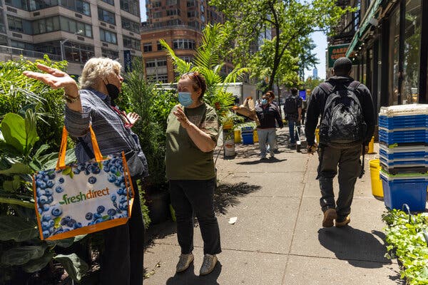 An unmasked woman and a masked woman chatting in Manhattan on Friday, the day after the Centers for Disease Control and Prevention lifted mask requirements in most settings for people who are fully vaccinated.