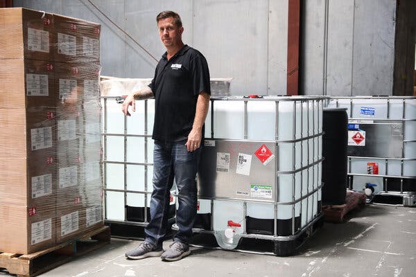 A Dark Door Spirits co-owner, Matt Allen, with large containers of hand sanitizer at the distillery’s warehouse in Tampa.
