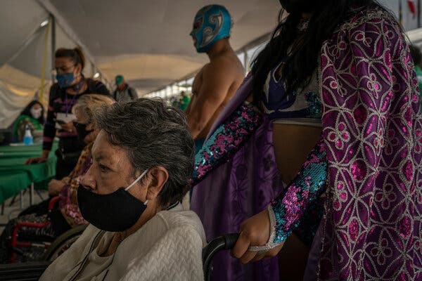 Lucha Libre wrestlers wheeling patients inside a vaccination tent in Mexico City this month.