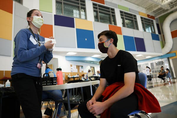 A teenager waiting for his Covid-19 shot at a vaccination site inside a school in Denver on Saturday.