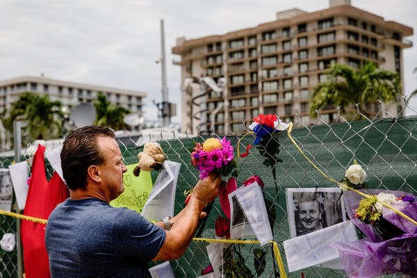 Chris Jeffers placed flowers on a barricade fence that has become a makeshift memorial near the site of the Champlain Towers South collapse site in Surfside, Fla.