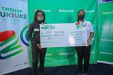 Safaricom plc Isaac Gathogu (L) hand over a dummy cheque of two million shillings to Maxine Wahome (Center) and her co-driver Linet Ayuko (L) during Safaricom cheque handover at Safaricom headquarter - Bizna Kenya