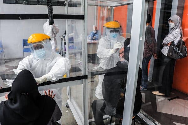 Health workers collecting specimen samples at a testing center in Medan, Indonesia, this week. The police raided a lab in the country and are investigating the reuse of swabs at an airport site.