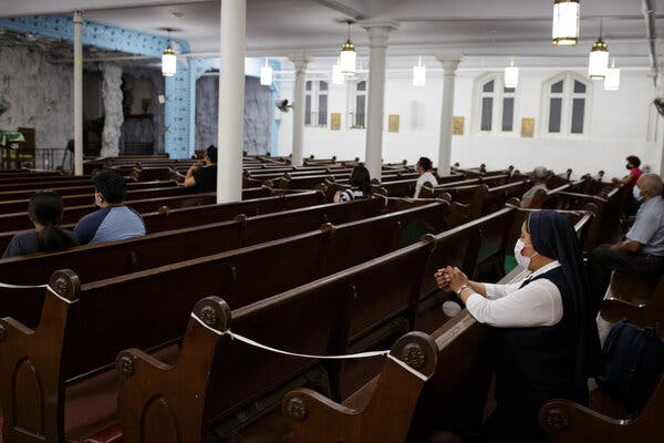 Parishioners during Thursday evening Spanish mass at Our Lady of Lourdes Church in Harlem. Many pews are blocked to create spacing due to Covid-19.