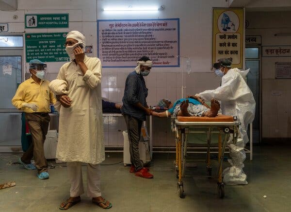 A man speaks on the phone as a doctor tries to revive his wife inside an emergency ward, in Bijnor district, Uttar Pradesh, India, on Tuesday.