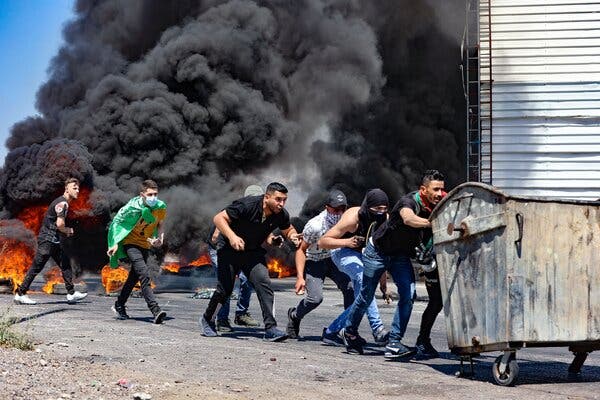 Palestinians, some of them youths, using a garbage container as as a barricade during confrontations with Israeli security forces on Friday near the West Bank city of Nablus.