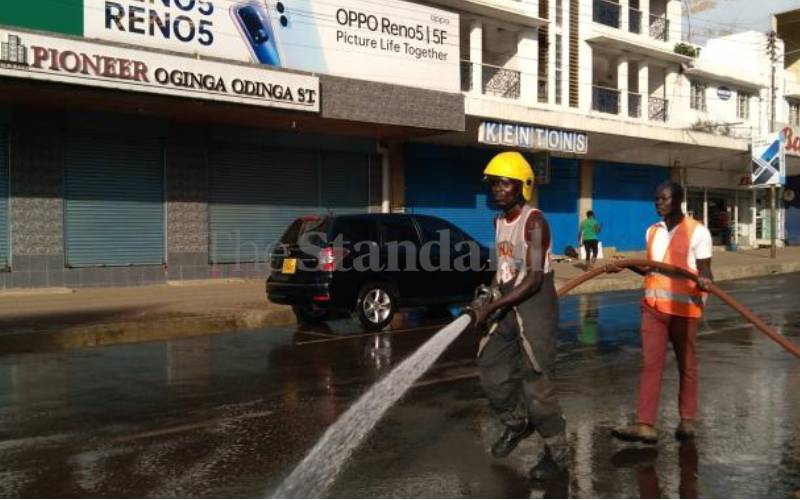 Residents wash the streets as President Uhuru Kenyatta arrives in Kisumu