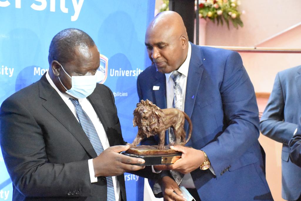 MKU founder Prof. Simon Gicharu (r) gifts Interior Cabinet Secretary Fred Matiang'i during the opening of the Mwai Kibaki Convention Centre on November 4, 2021. 