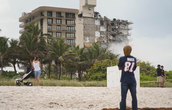 Onlookers at the beach on Friday at the site of the Champlain Towers condominium collapse in Surfside, Fla.