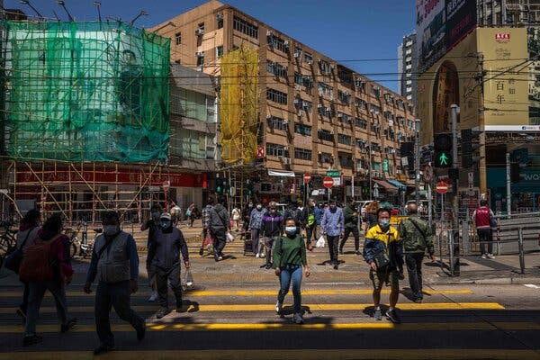 Wearing face masks in Hong Kong on Tuesday. Two years after the pandemic was declared, the city is experiencing its worst outbreak yet.