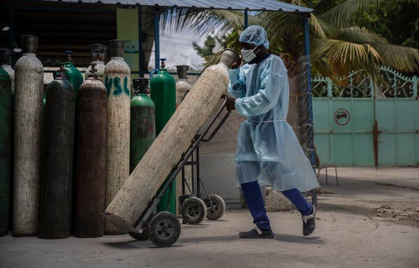 A hospital employee transporting oxygen tanks in Port-au-Prince, Haiti, in June.