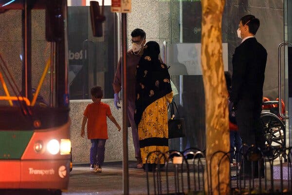 A family, among more than 90 evacuated Australian citizens and Afghans, stepping off a bus at a hotel to begin a pandemic quarantine in Perth on Friday.