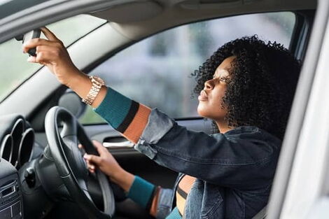 Woman in a car checking a mirror