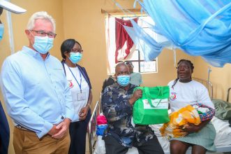 Governor, County Government of Homabay H.E. Hon. Cyprian Awiti gifts Jecinter Akinyi with an M-Pesa Foundation Hamper, assisted by Florence Adhiambo nurse in charge of Ndhiwa Sub County Hospital and MPESA Foundation Mr Les Baillie(left)Chief Executive Officer. The event was held at Ndhiwa Sub County Hospital Homabay County - Bizna Kenya