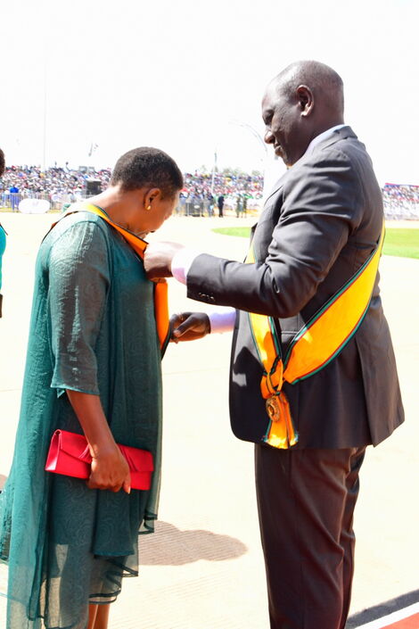 Deputy President William Ruto assisting Mama Racheal Ruto put on her ribbon during Madaraka Day celebrations on June 1, 2022.
