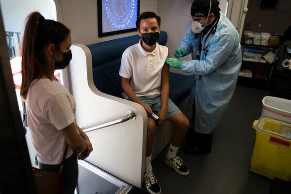 Rosie Manzo, left, watching as her brother, Esteban, 15, got the Pfizer vaccine at a mobile clinic in Santa Ana, Calif., in August.