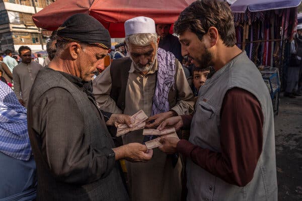 Money changers working with customers at their stalls in Kabul in August. Halawa, the informal banking network, is crucial to many Afghans.