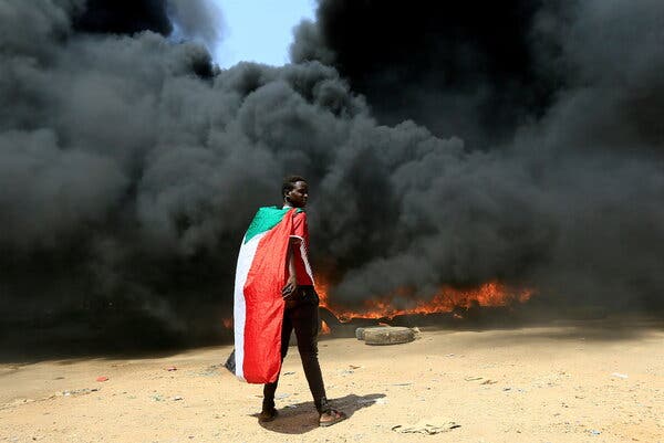 A man wore Sudan’s flag as a pile of tires burned during a protest in Khartoum, Sudan, last week.