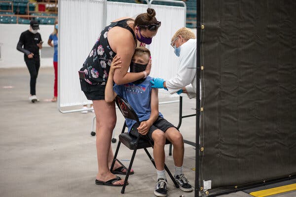 Skyler Hamm, 12, received his first dose of the Pfizer-BioNTech vaccine while being comforted by his mother, Jessica Metz, during a mass vaccination event for 12- to 15-year-olds in Albuquerque, N.M., last month.