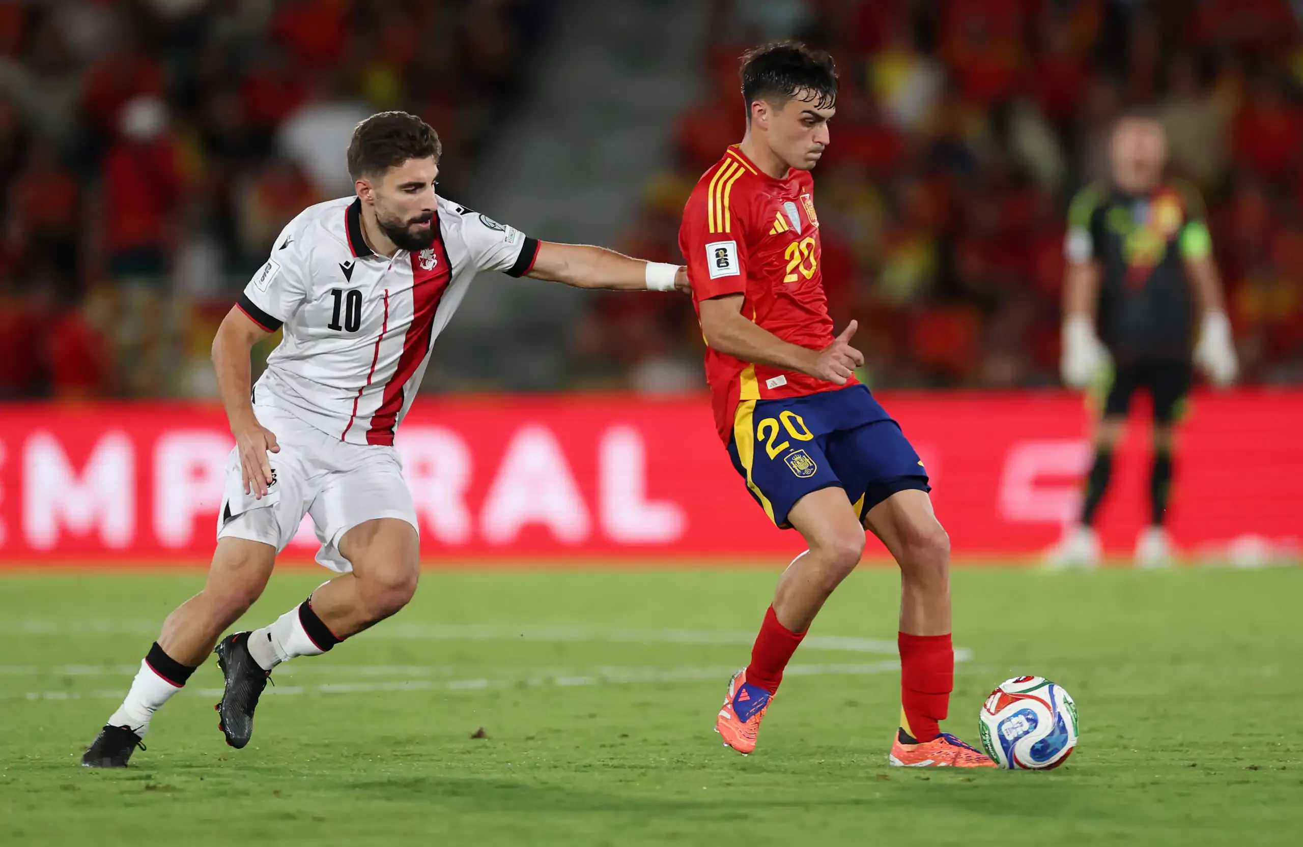 Georgia and Spain football players competing on the field during a World Cup qualifier.
